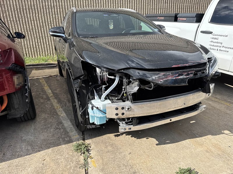Un Lexus NX negro antes de la reparación, con la defensa delantera, la parrilla y el faro arrancados