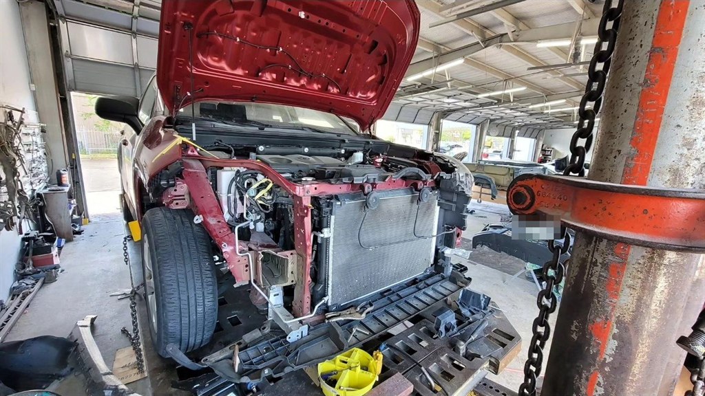 A pickup with its front end opened up on the frame straightening bench, where structure and sensors are checked