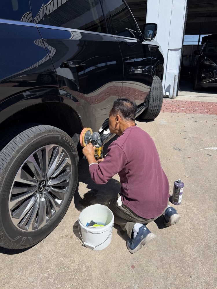 A Nova Body Shop technician polishing the side of a black SUV with a buffer